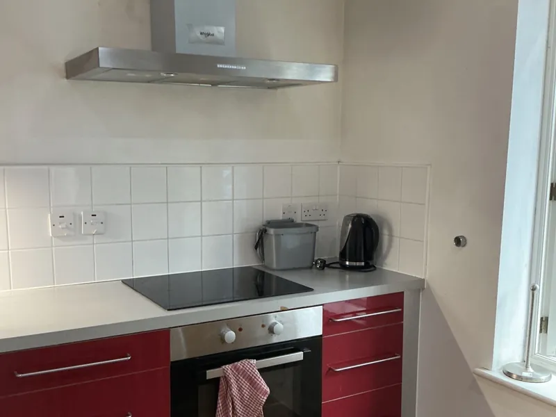 Clean kitchen with red units, an extractor hood and a built-in oven